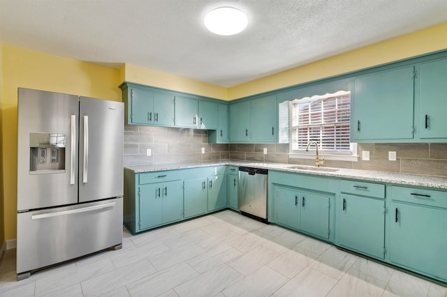 kitchen with stainless steel appliances, light countertops, a sink, and backsplash