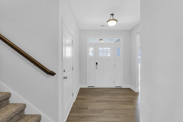 entryway featuring dark wood-type flooring, baseboards, and stairs