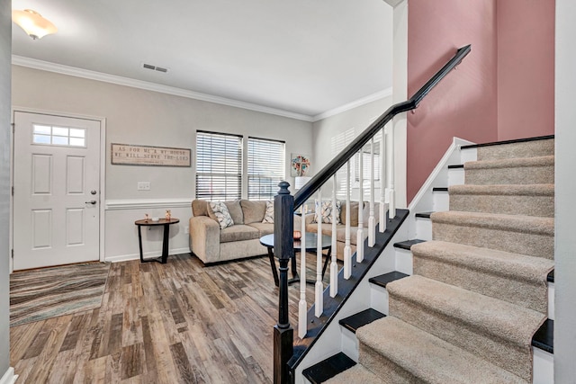 entryway featuring stairs, visible vents, wood finished floors, and ornamental molding