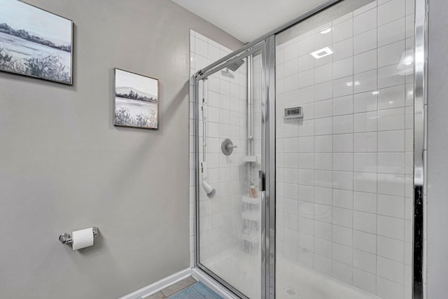 bathroom with a stall shower, tile patterned flooring, and baseboards