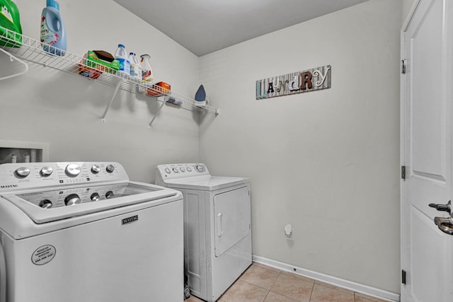 washroom with laundry area, baseboards, washer and clothes dryer, and light tile patterned flooring