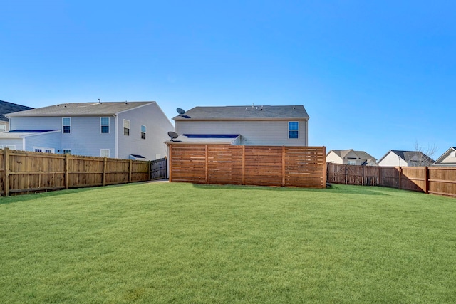 rear view of house featuring a fenced backyard, a residential view, and a lawn