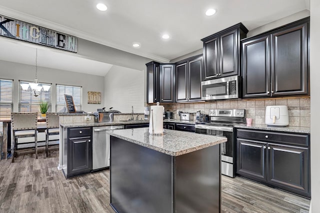 kitchen with a peninsula, a kitchen island, appliances with stainless steel finishes, tasteful backsplash, and pendant lighting