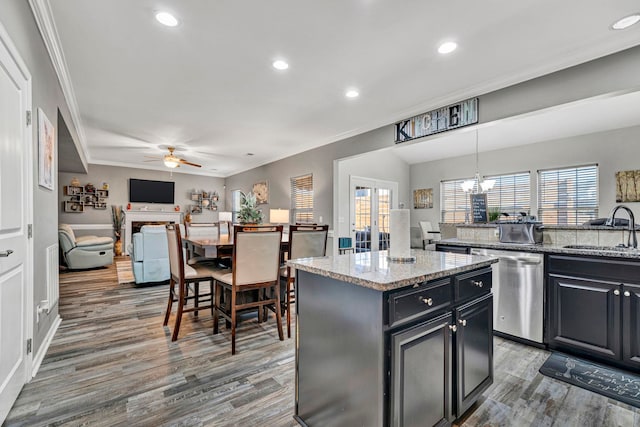 kitchen with hanging light fixtures, a kitchen island, light stone counters, and a sink