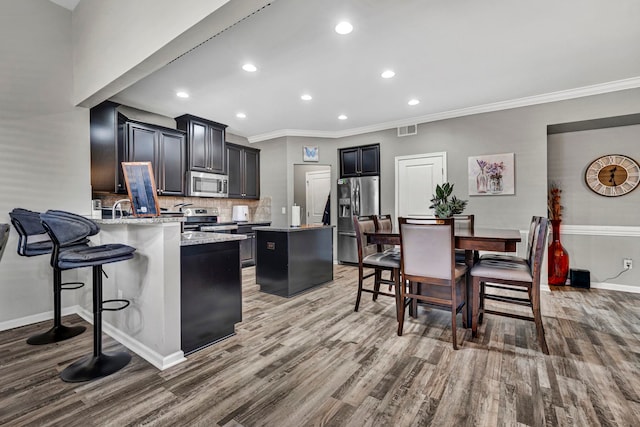 kitchen with light stone counters, a center island, visible vents, appliances with stainless steel finishes, and a peninsula