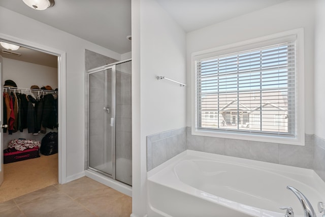 full bathroom with a walk in closet, tile patterned flooring, a shower stall, and a bath