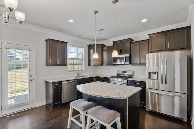 kitchen featuring a breakfast bar, a sink, a kitchen island, appliances with stainless steel finishes, and pendant lighting