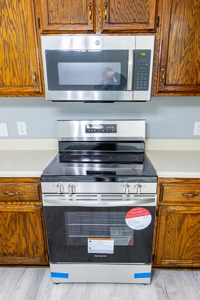 kitchen with appliances with stainless steel finishes, brown cabinets, and light countertops