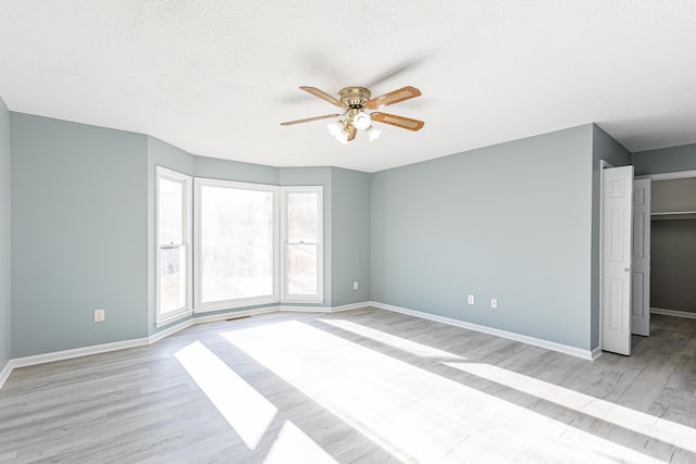 unfurnished bedroom with a textured ceiling, a ceiling fan, light wood-style flooring, and baseboards