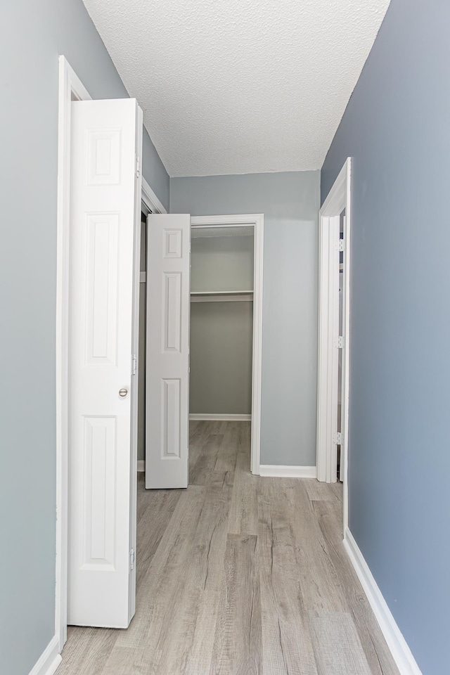 unfurnished bedroom featuring light wood-style flooring, baseboards, and a closet