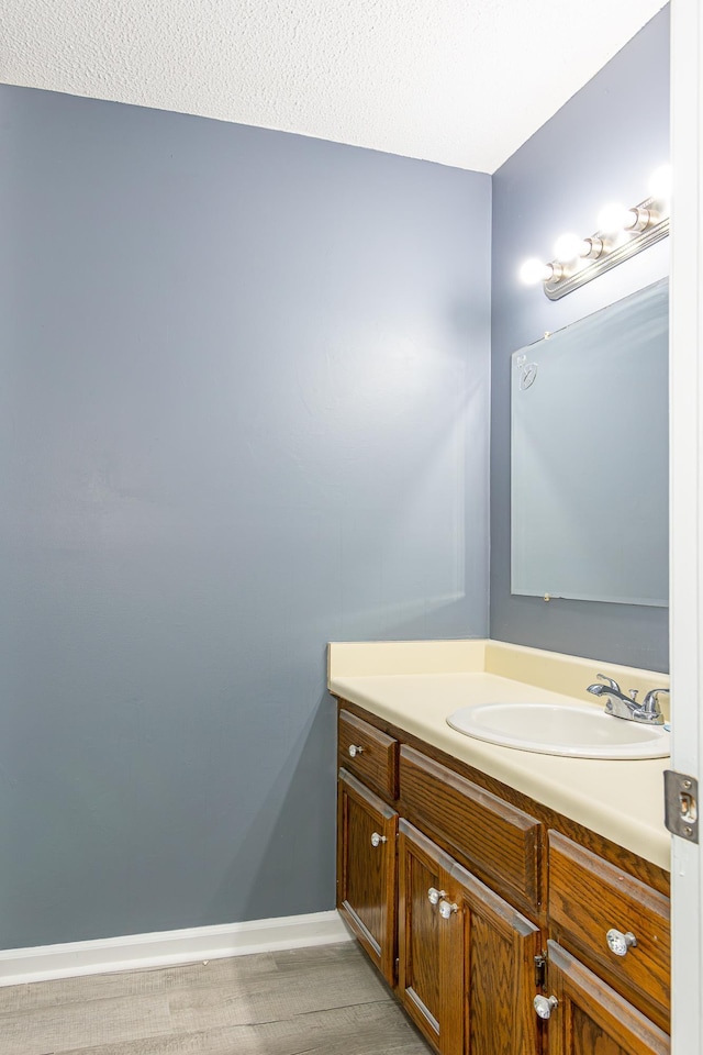 bathroom with wood finished floors, vanity, and baseboards