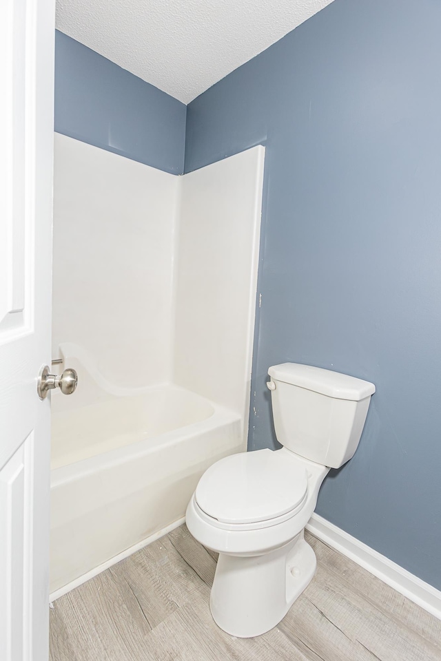 bathroom featuring a textured ceiling, wood finished floors, toilet, and baseboards