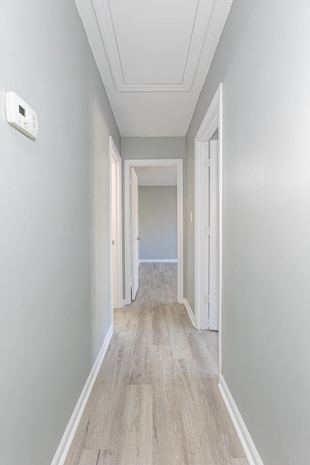 corridor featuring light wood-type flooring and baseboards