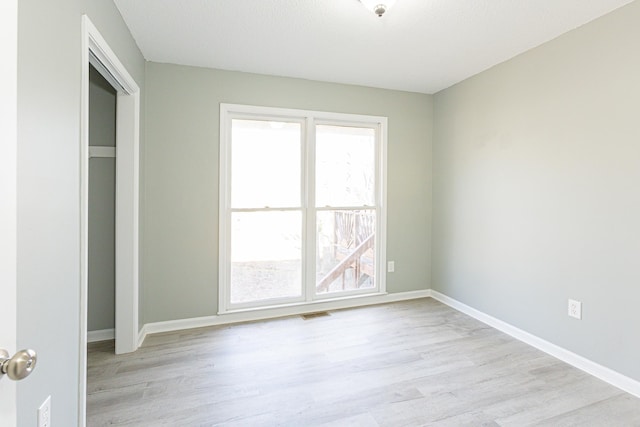 unfurnished room featuring light wood-type flooring, visible vents, and baseboards