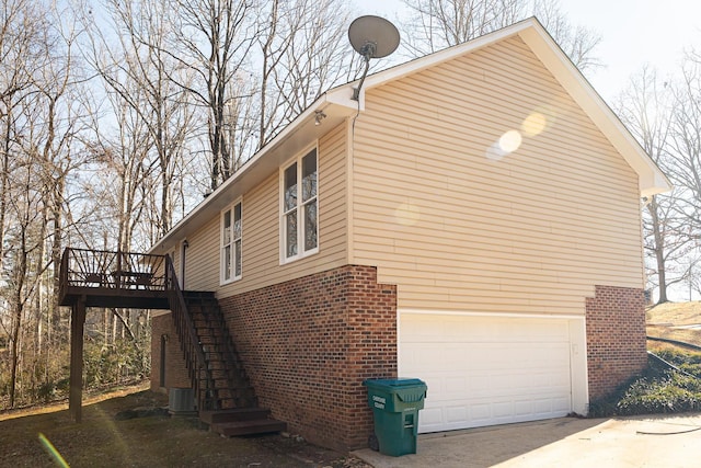 view of home's exterior with stairs, concrete driveway, brick siding, and an attached garage