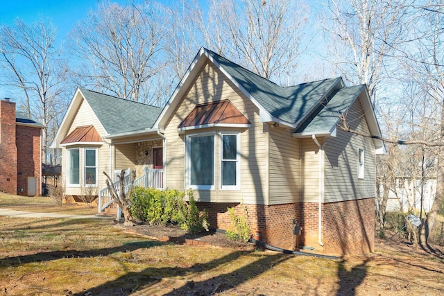 bungalow featuring a shingled roof, a front yard, and brick siding