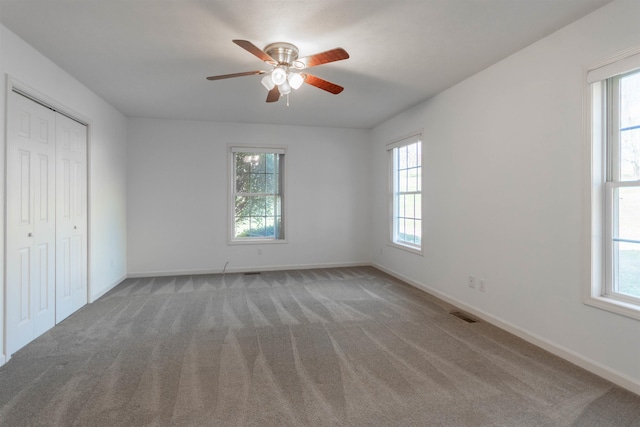 unfurnished bedroom featuring light carpet, baseboards, visible vents, ceiling fan, and a closet