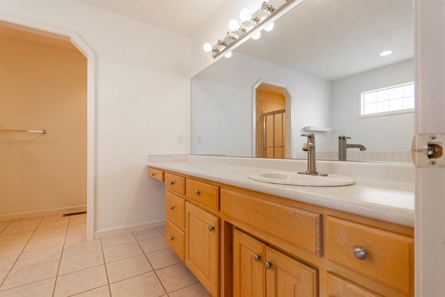 full bathroom featuring a shower with shower door, vanity, baseboards, and tile patterned floors