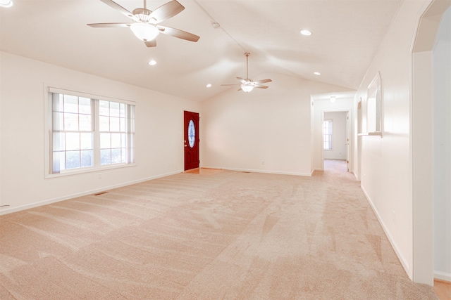 empty room with lofted ceiling, light colored carpet, plenty of natural light, and baseboards