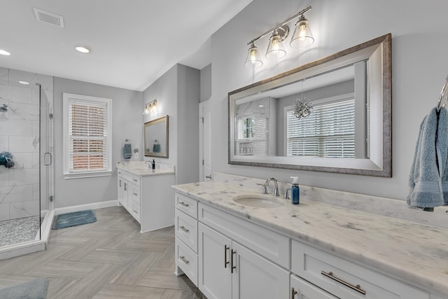 full bathroom featuring two vanities, a sink, visible vents, baseboards, and a stall shower