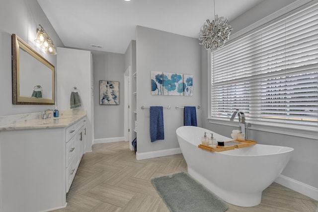 bathroom with a freestanding tub, baseboards, visible vents, and vanity