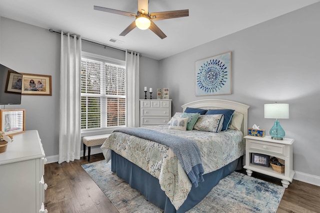 bedroom featuring baseboards, visible vents, dark wood finished floors, and a ceiling fan