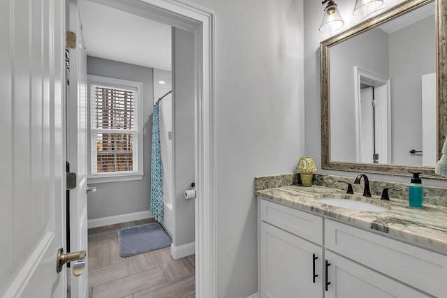 full bathroom with baseboards, shower / bath combination with curtain, and vanity