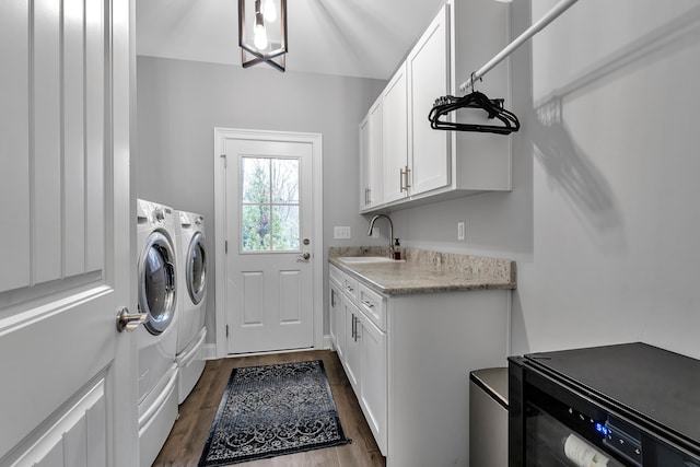 washroom featuring cabinet space, dark wood-style floors, wine cooler, washing machine and dryer, and a sink