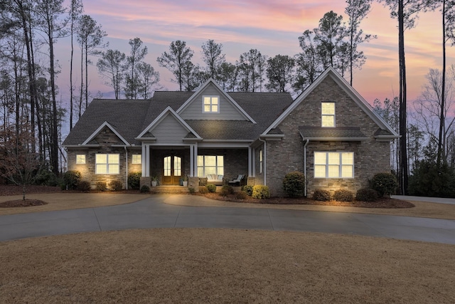 craftsman inspired home featuring driveway, covered porch, and brick siding