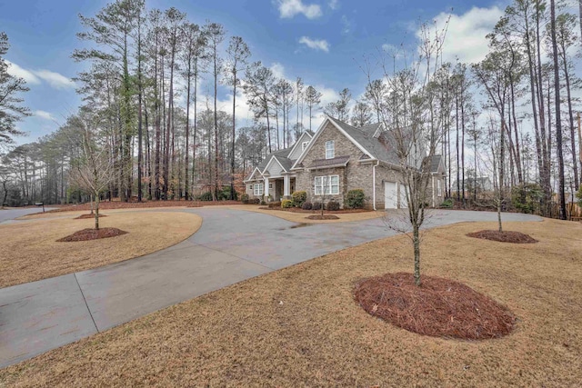 view of front of house featuring a garage, stone siding, curved driveway, and a front yard