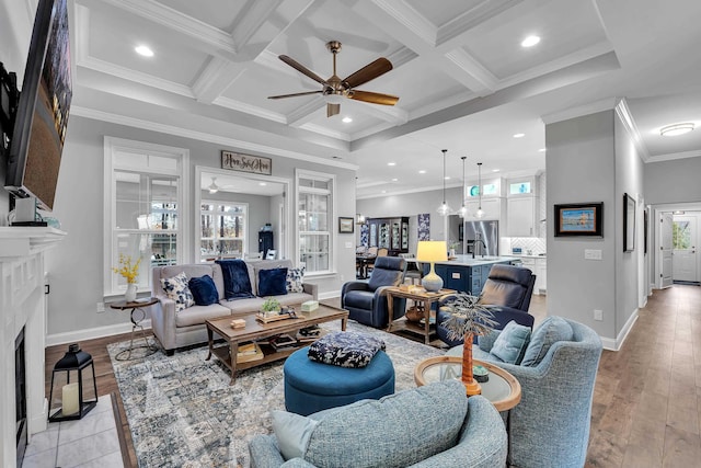 living room featuring coffered ceiling, ornamental molding, light wood-style floors, beam ceiling, and a high end fireplace