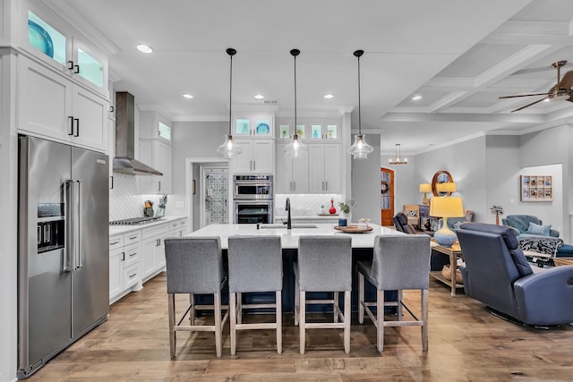 kitchen featuring appliances with stainless steel finishes, open floor plan, glass insert cabinets, and wall chimney exhaust hood