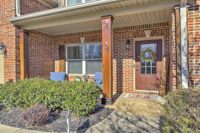 entrance to property featuring covered porch and brick siding