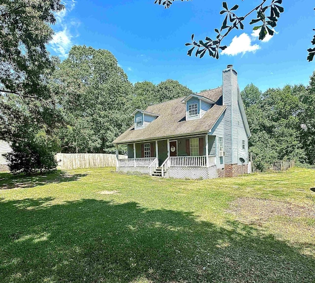 view of front of property with a porch, a front lawn, a chimney, and fence