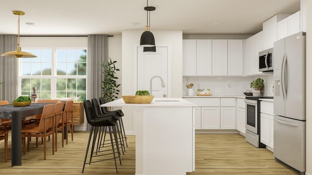 kitchen featuring decorative light fixtures, a center island with sink, stainless steel appliances, light countertops, and white cabinets