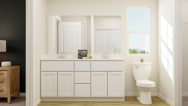 bathroom with toilet, wood finished floors, a sink, baseboards, and double vanity