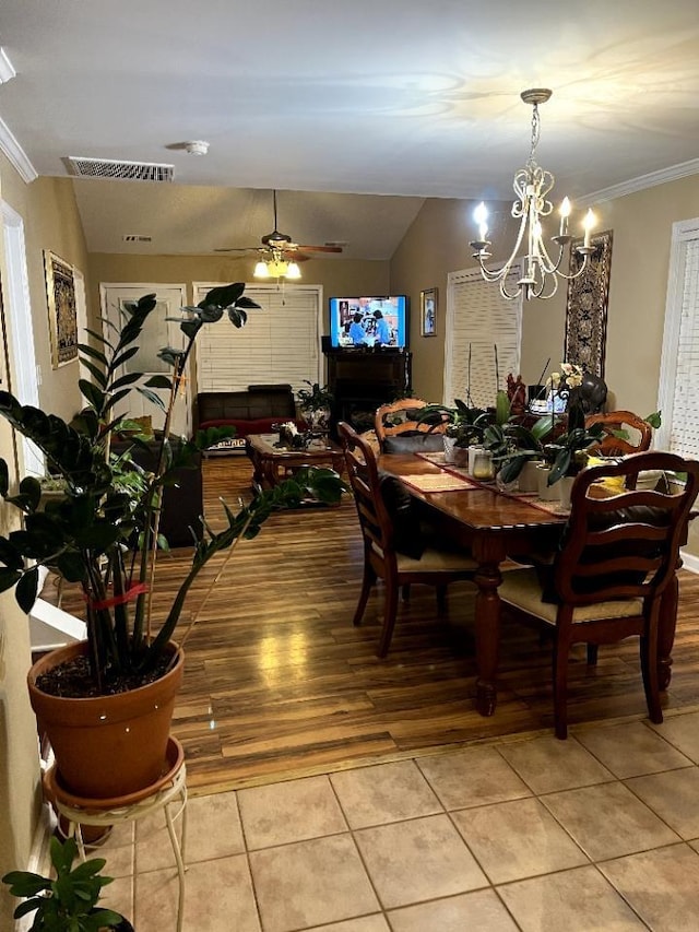 dining space featuring lofted ceiling, light tile patterned floors, visible vents, and ceiling fan with notable chandelier