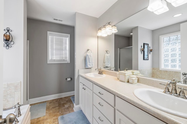 bathroom featuring a garden tub, double vanity, a sink, and visible vents