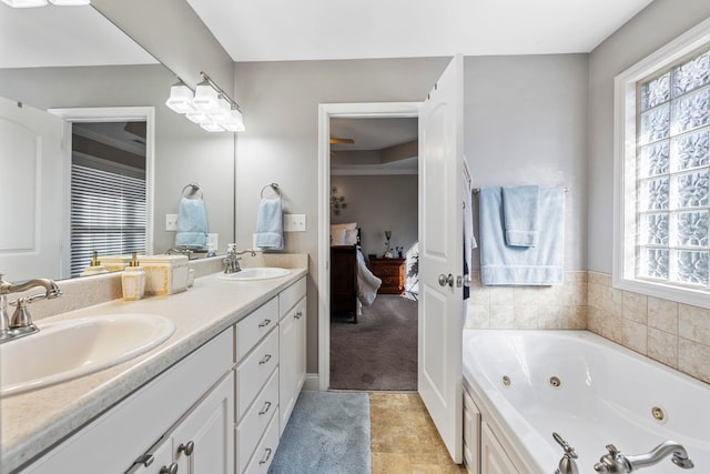 full bathroom with double vanity, a tub with jets, a sink, and ensuite bathroom