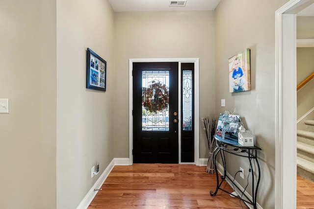 foyer featuring stairs, wood finished floors, visible vents, and baseboards