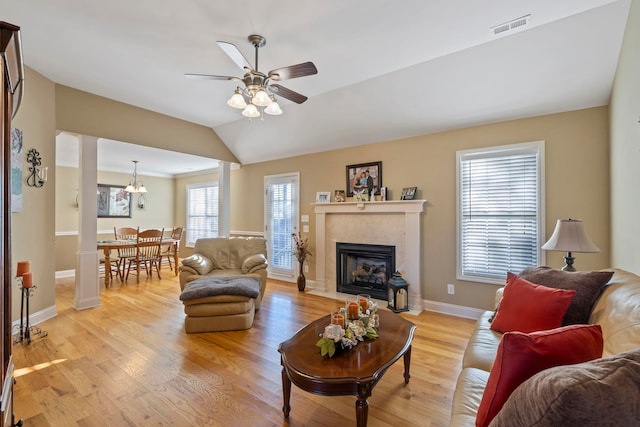 living room with lofted ceiling, light wood-style flooring, a fireplace with flush hearth, visible vents, and baseboards