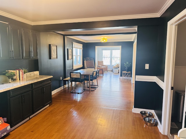 dining area featuring light wood-style floors, baseboards, and crown molding