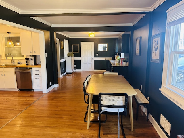 dining room featuring light wood finished floors, visible vents, baseboards, and crown molding