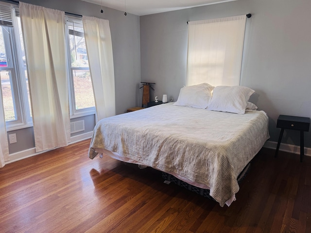 bedroom featuring visible vents, baseboards, and wood finished floors