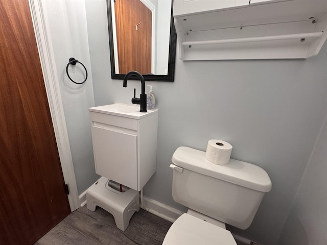 half bathroom with toilet, baseboards, and vanity