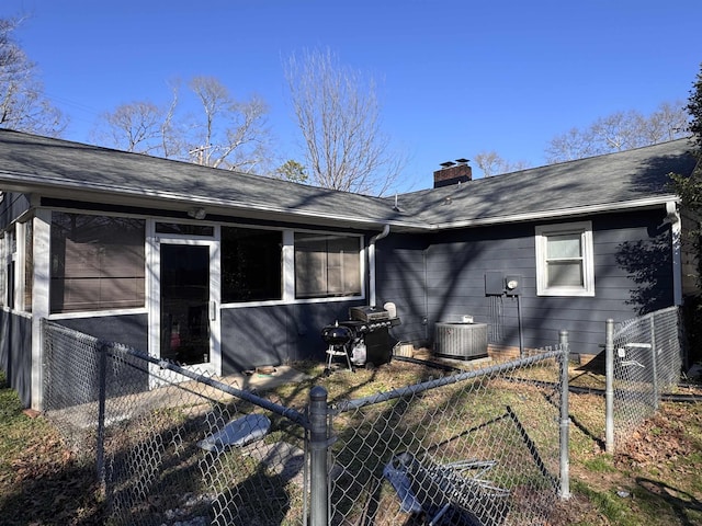 back of house featuring a shingled roof, fence private yard, a chimney, and central AC unit