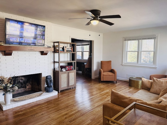 living area featuring a fireplace, visible vents, ceiling fan, wood finished floors, and baseboards