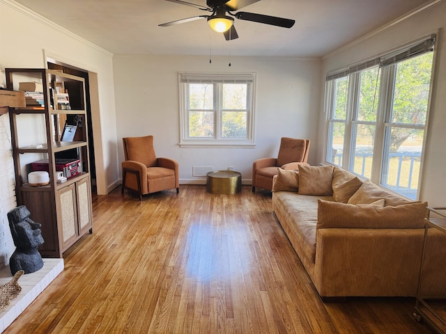 living area featuring crown molding, a healthy amount of sunlight, visible vents, and light wood-style floors