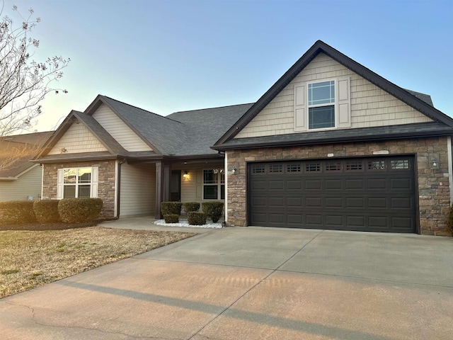 craftsman-style house featuring stone siding, a shingled roof, and concrete driveway