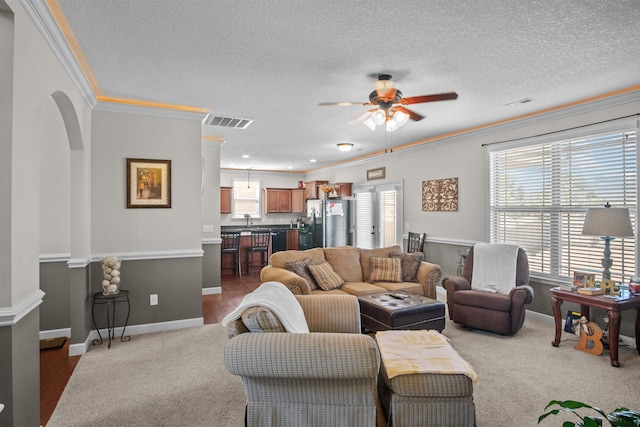 living area with light carpet, visible vents, arched walkways, baseboards, and ceiling fan